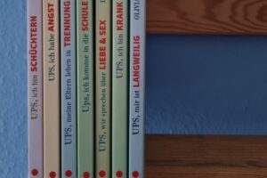Sieben Bücher aus der Ups-Reihe vom Humboldtverlag stehen nebeneinander aufgereiht vor einer blauen Wand.